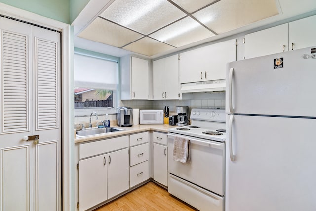 kitchen with light hardwood / wood-style floors, tasteful backsplash, white cabinets, white appliances, and sink