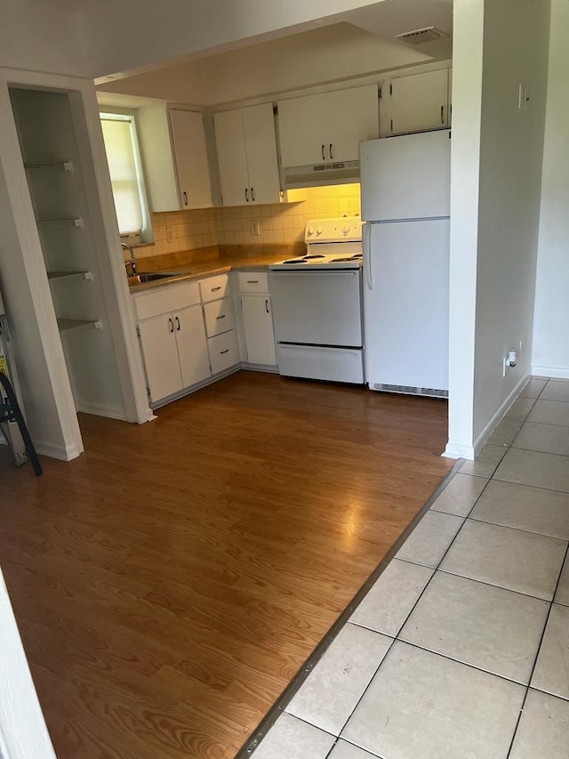 kitchen featuring light tile patterned flooring, white cabinets, backsplash, white appliances, and sink