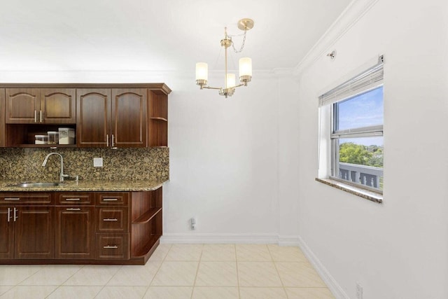 kitchen with backsplash, light stone countertops, crown molding, dark brown cabinets, and sink