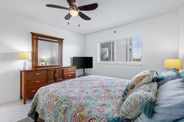 bedroom with ceiling fan, light tile patterned floors, and a textured ceiling