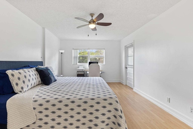 bedroom featuring light hardwood / wood-style floors, ceiling fan, and a textured ceiling