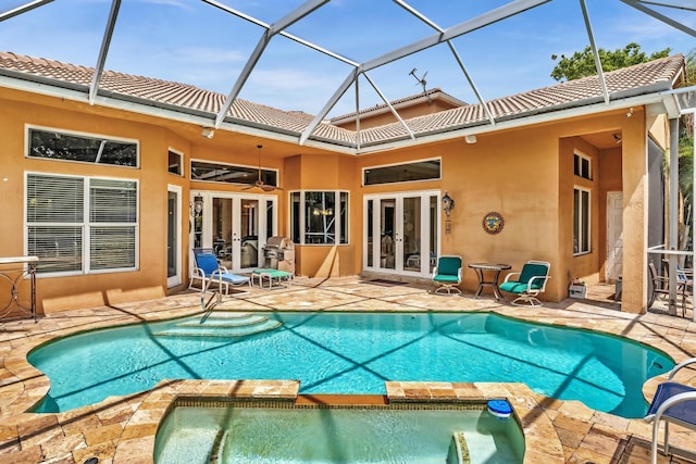 view of pool with glass enclosure, ceiling fan, a patio area, and french doors