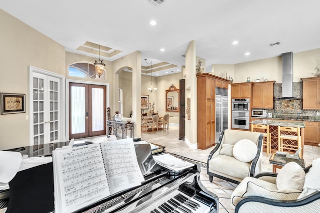 living room featuring french doors, an inviting chandelier, and a raised ceiling