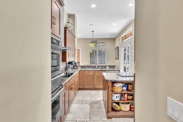 kitchen with stainless steel oven, sink, light stone counters, pendant lighting, and decorative backsplash