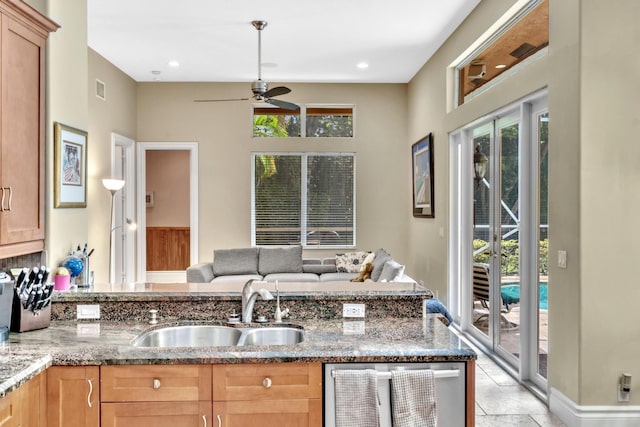 kitchen with ceiling fan, dishwasher, light stone counters, and sink