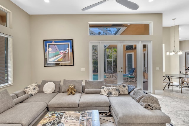 living room with french doors and ceiling fan with notable chandelier