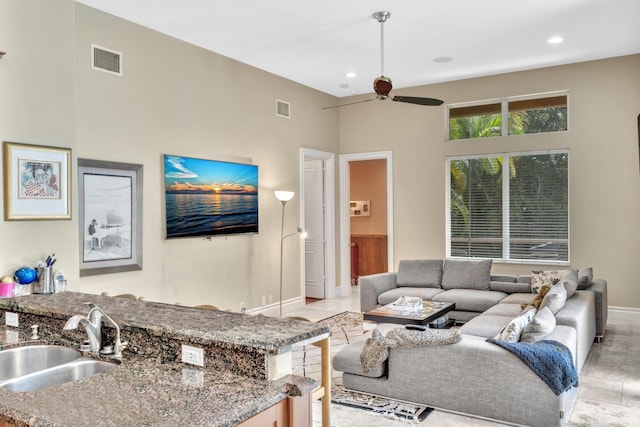 living room with a high ceiling, light hardwood / wood-style flooring, ceiling fan, and sink