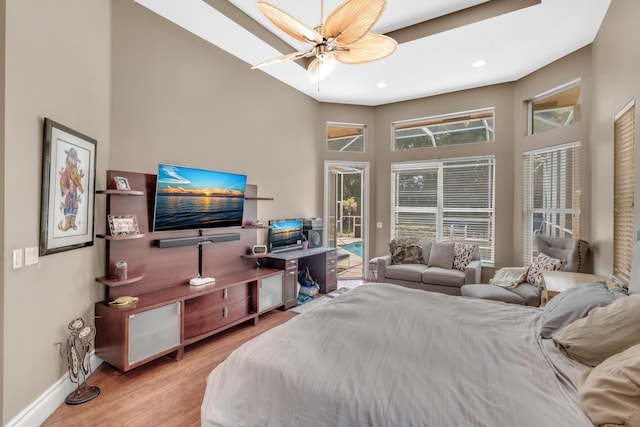 bedroom featuring access to exterior, a high ceiling, light hardwood / wood-style flooring, and ceiling fan