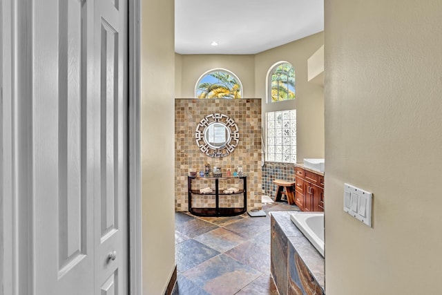 bathroom with vanity and tiled tub