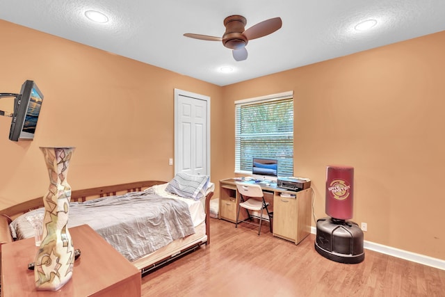 bedroom featuring ceiling fan, light hardwood / wood-style floors, and a textured ceiling