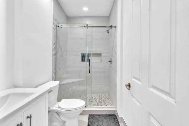 bathroom with tile patterned flooring, vanity, an enclosed shower, and toilet