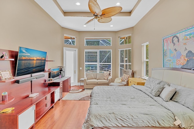 bedroom featuring ceiling fan, a raised ceiling, wood-type flooring, and a high ceiling