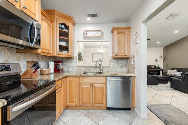 kitchen featuring light stone countertops, sink, decorative backsplash, light tile patterned floors, and appliances with stainless steel finishes