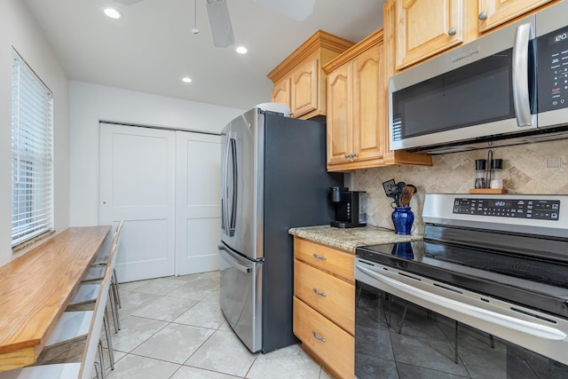 kitchen featuring light brown cabinets, ceiling fan, light tile patterned floors, appliances with stainless steel finishes, and tasteful backsplash