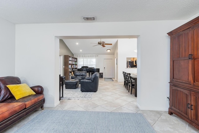 living room featuring ceiling fan, light tile patterned flooring, and a textured ceiling