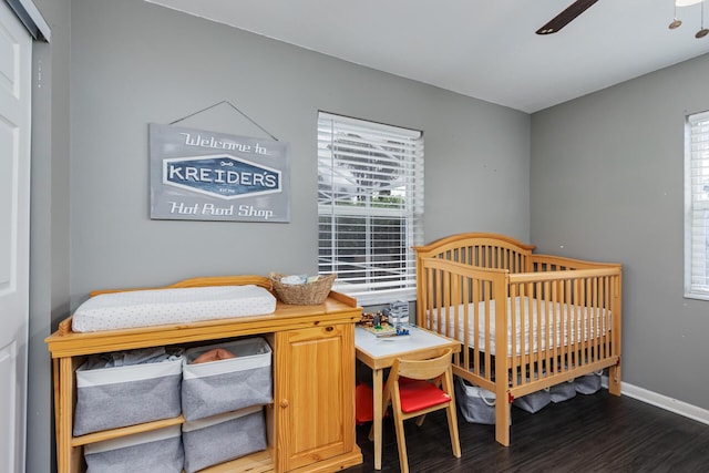 bedroom with multiple windows, ceiling fan, a crib, and dark hardwood / wood-style floors