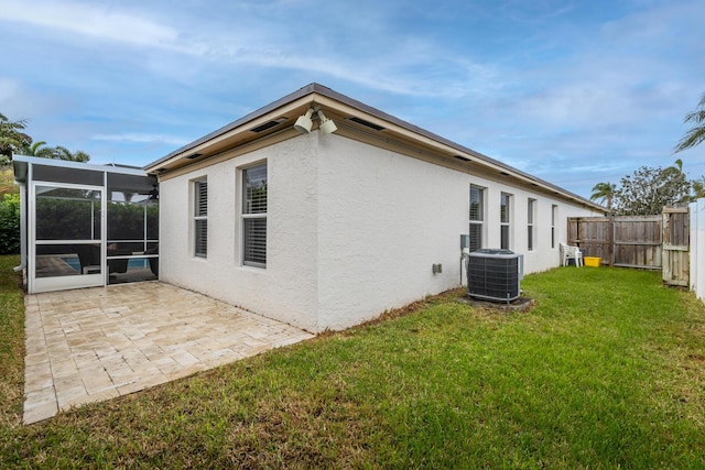 rear view of house with a lawn, central air condition unit, a sunroom, and a patio