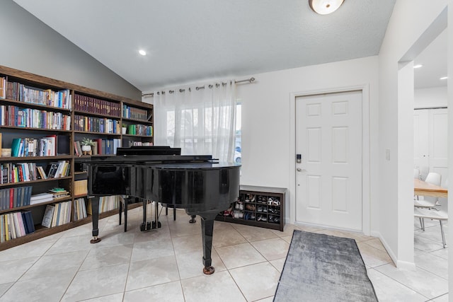 interior space with light tile patterned floors, a textured ceiling, and vaulted ceiling