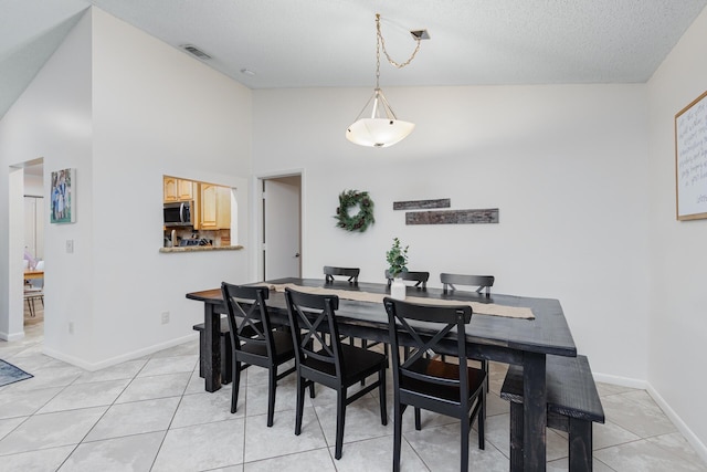 dining space with light tile patterned floors, a textured ceiling, and high vaulted ceiling