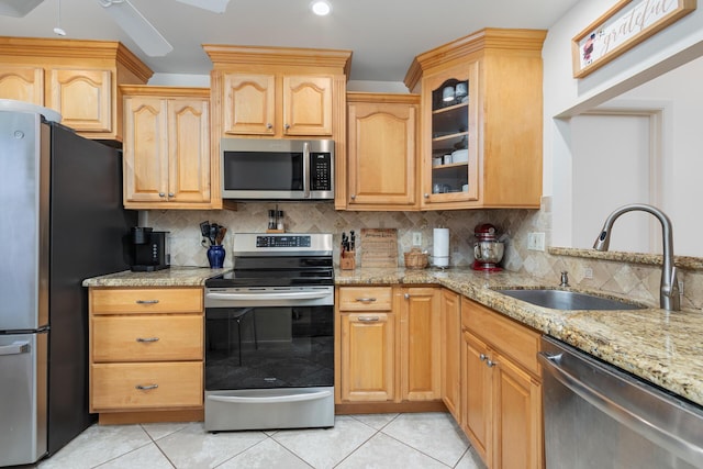 kitchen with sink, light stone countertops, stainless steel appliances, and tasteful backsplash