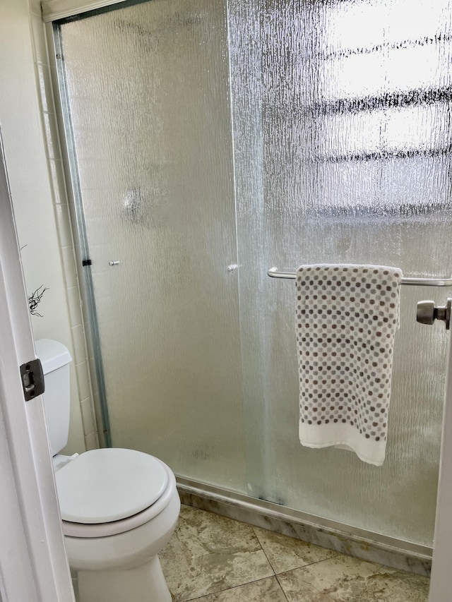 bathroom with tile patterned flooring, toilet, and an enclosed shower