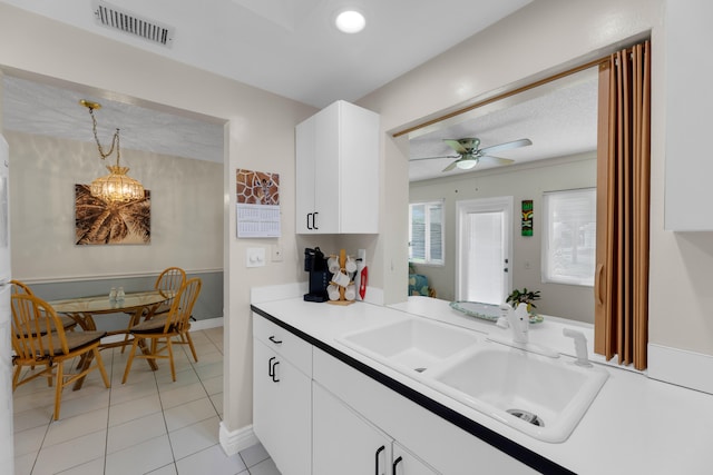 kitchen featuring sink, ceiling fan with notable chandelier, white cabinets, light tile patterned floors, and decorative light fixtures