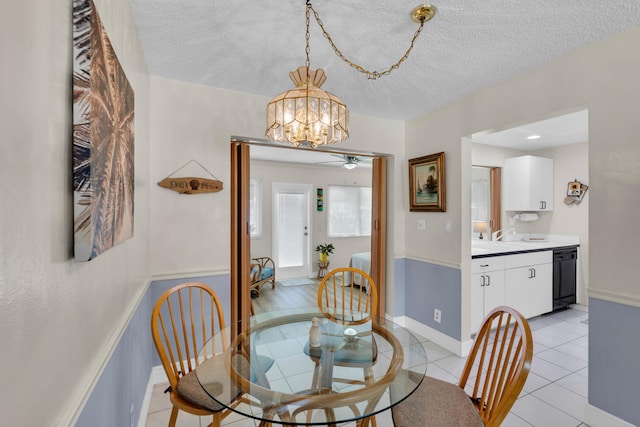 tiled dining area with ceiling fan with notable chandelier, a textured ceiling, and sink