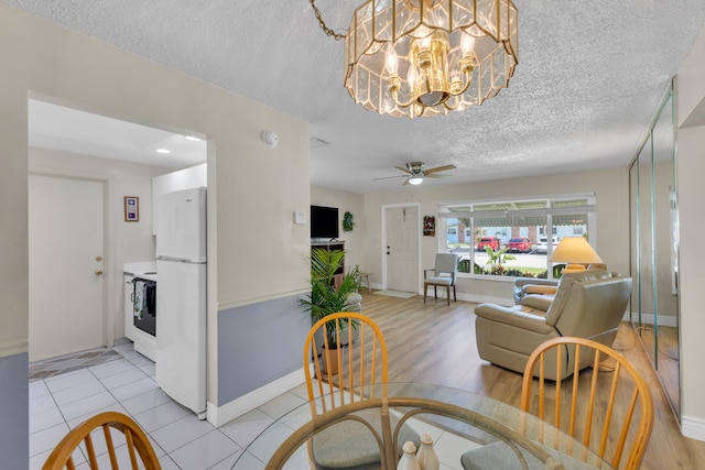 dining area featuring a textured ceiling, ceiling fan with notable chandelier, and light wood-type flooring