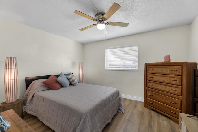 bedroom with ceiling fan, a textured ceiling, and light hardwood / wood-style floors