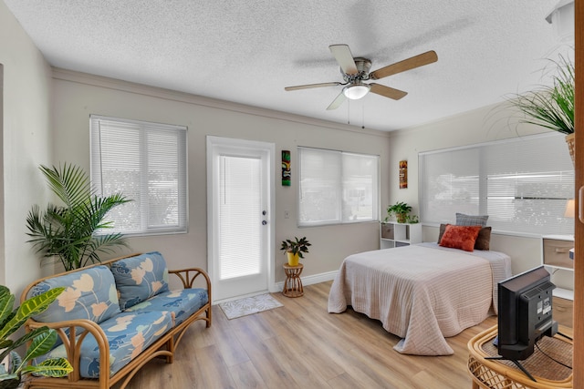 bedroom with ceiling fan, a textured ceiling, light hardwood / wood-style flooring, and multiple windows