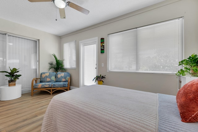 bedroom featuring light hardwood / wood-style floors, ceiling fan, and a textured ceiling