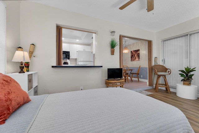 bedroom featuring ceiling fan, white refrigerator, and light hardwood / wood-style floors