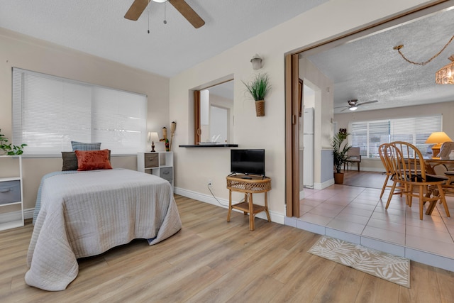 bedroom with light wood-type flooring, ceiling fan, and a textured ceiling