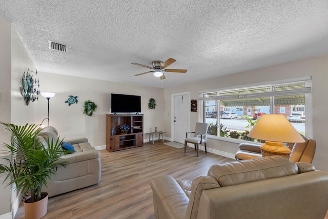 living room with a textured ceiling, wood-type flooring, and ceiling fan