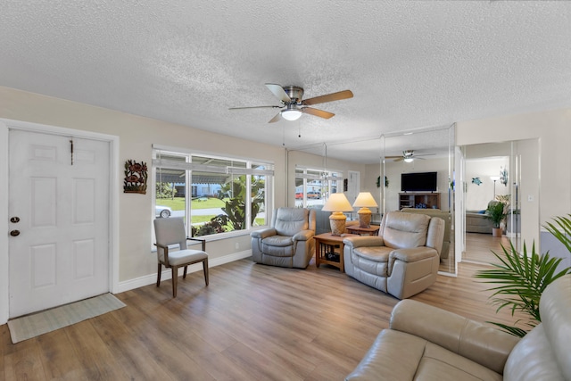 living room featuring ceiling fan, hardwood / wood-style flooring, and a textured ceiling