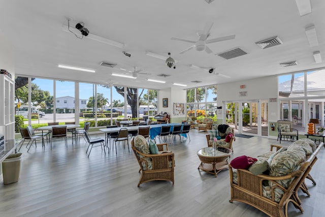 living room featuring a wall of windows, ceiling fan, french doors, and light hardwood / wood-style flooring