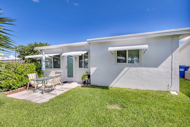 back of property with a lawn and a patio area