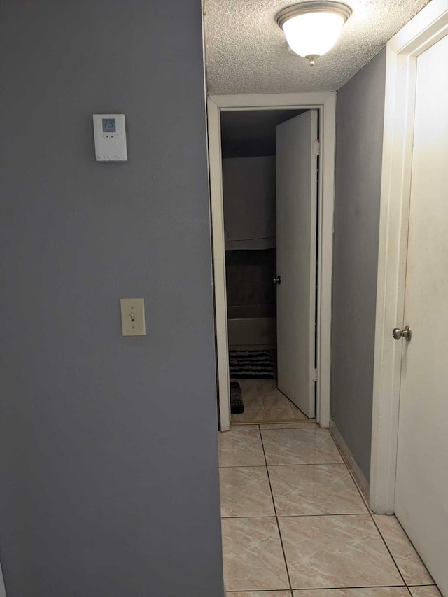 hall featuring a textured ceiling and light tile patterned floors