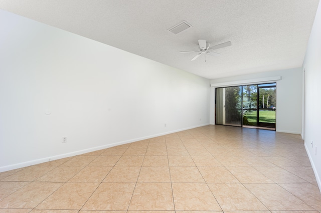 empty room with a textured ceiling, ceiling fan, and light tile patterned floors