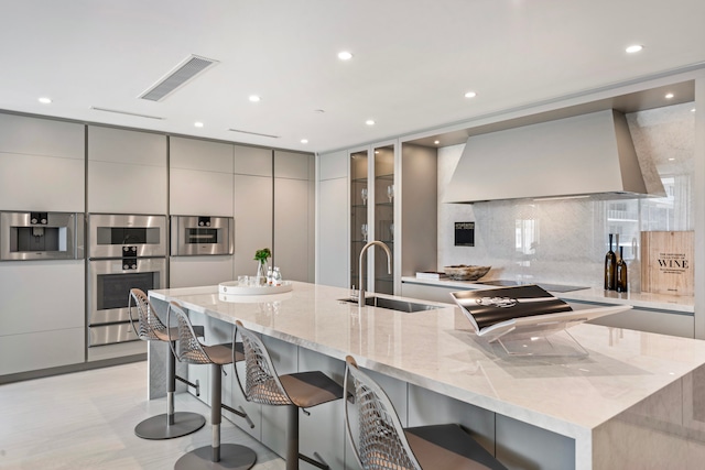 kitchen with gray cabinetry, double oven, sink, and a breakfast bar