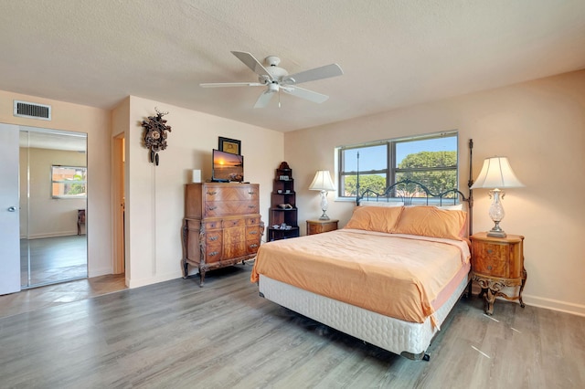 bedroom with ceiling fan, hardwood / wood-style flooring, and a textured ceiling