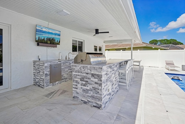 view of patio with an outdoor kitchen, grilling area, ceiling fan, an outdoor bar, and a swimming pool