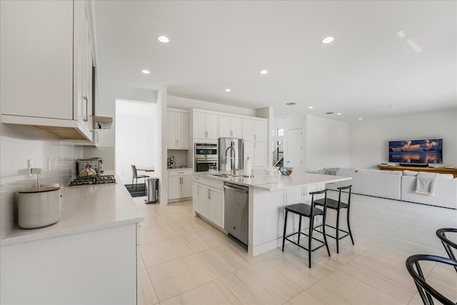 kitchen with white cabinets, a kitchen breakfast bar, a spacious island, and appliances with stainless steel finishes