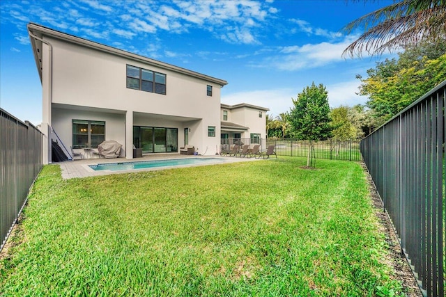 rear view of property with a fenced in pool, a patio area, and a lawn