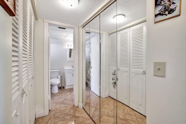 hallway featuring a textured ceiling and light tile patterned flooring