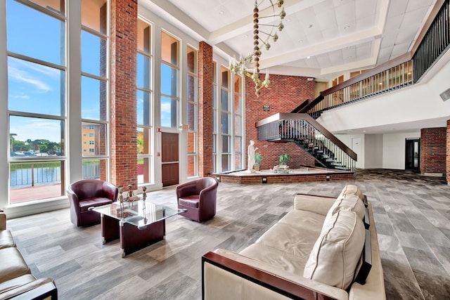 interior space featuring an inviting chandelier, a towering ceiling, brick wall, and hardwood / wood-style floors