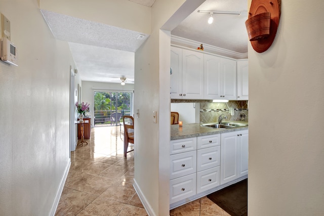 interior space featuring rail lighting, light tile patterned floors, a textured ceiling, crown molding, and sink