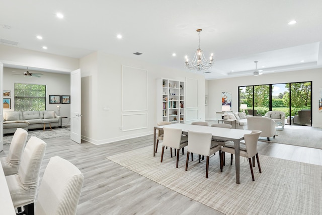 dining room featuring ceiling fan with notable chandelier and light hardwood / wood-style floors