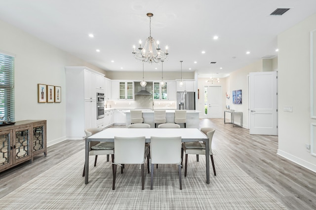 dining space featuring an inviting chandelier and light wood-type flooring