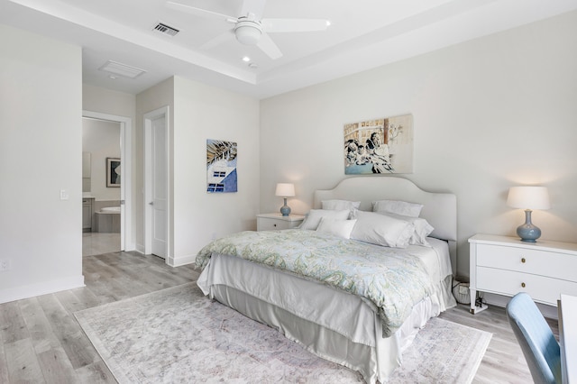 bedroom with light wood-type flooring, ceiling fan, and ensuite bathroom